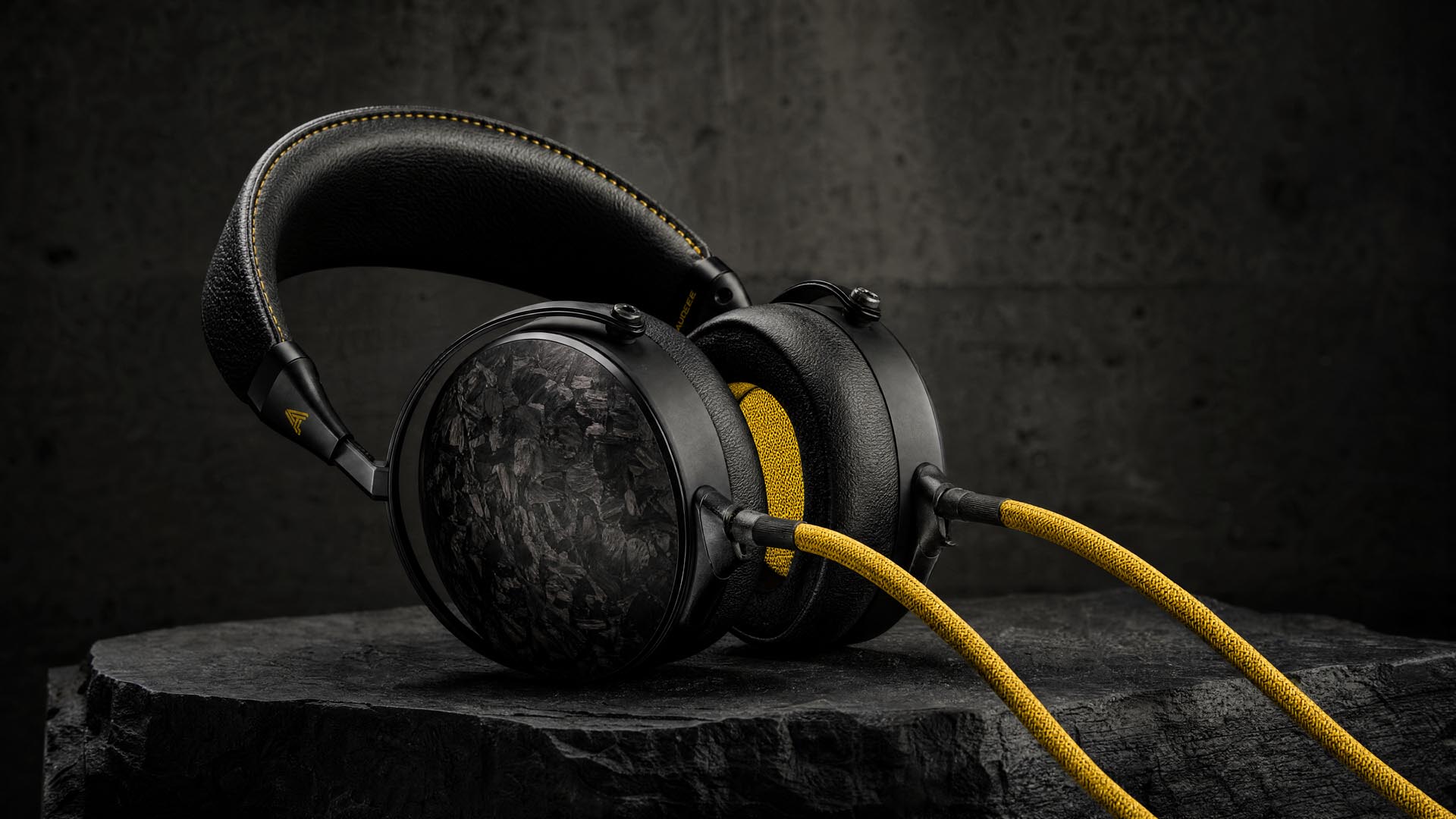 Black headphones with a yellow cable in a product visual
